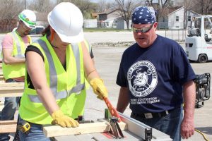 A photo of a former student of the HCCTP works hands-on as an instructor oversees the process.