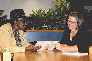 A featured photo of a former student and tutor in the SSC Adult Volunteer Literacy Tutoring Program reading together.